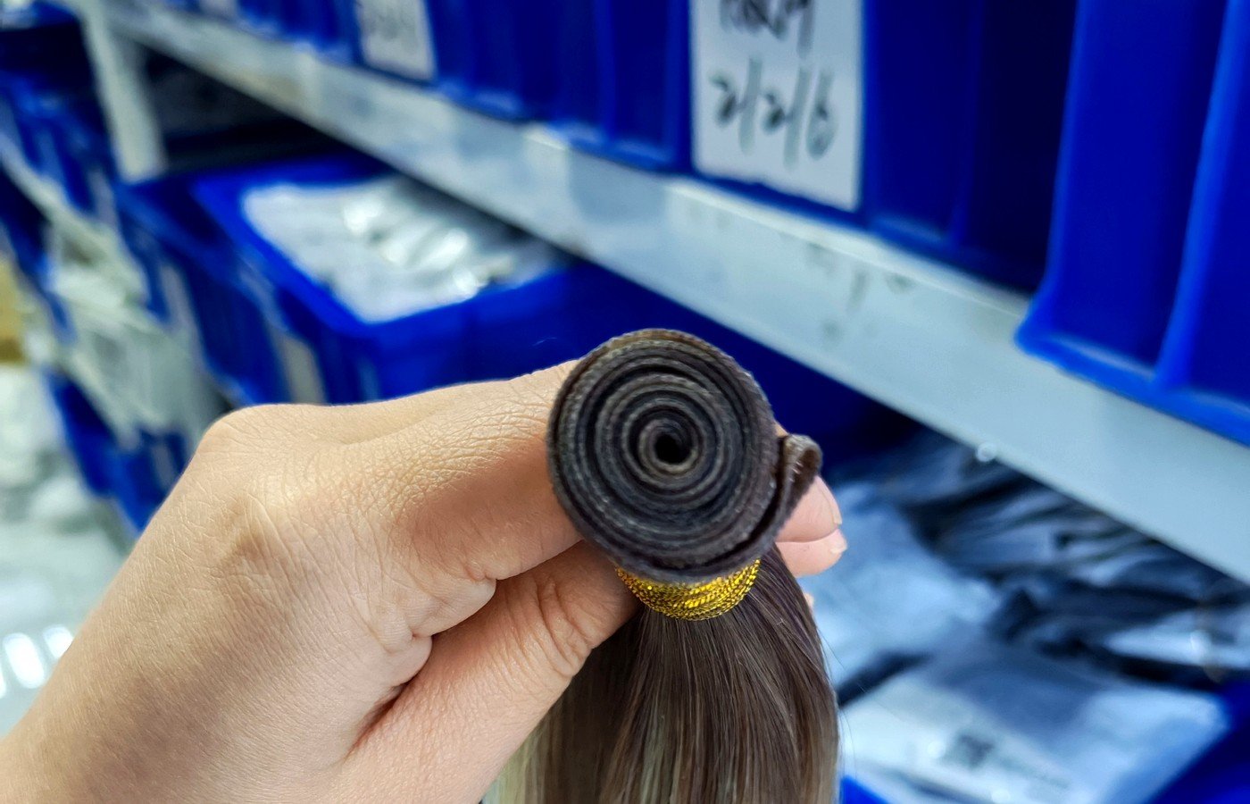 Close-up of thin single hand-tied weft seam rolled for salon buyer QC on wholesale Virgin human hair